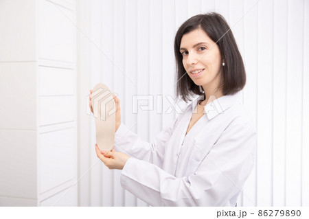 Doctor holding orthopedic insoles in his hands. Orthopedist tests the medical device. Orthopedic insoles on a white. Foot care. Flat Feet Correction. Prevention of flat feet and foot diseases. Doctor holding orthopedic insoles in his hands. Orthopedist tests the medical device. Orthopedic insoles on a white. Foot care. Flat Feet Correction. Prevention of flat feet and foot diseases. 86279890