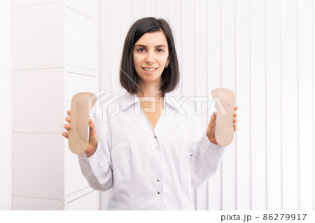 Doctor holding orthopedic insoles in his hands. Orthopedist tests the medical device. Orthopedic insoles on a white. Foot care. Flat Feet Correction. Prevention of flat feet and foot diseases. Doctor holding orthopedic insoles in his hands. Orthopedist tests the medical device. Orthopedic insoles on a white. Foot care. Flat Feet Correction. Prevention of flat feet and foot diseases. 86279917