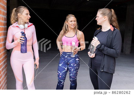Sporty beautiful young women of different body types talking and drinking water from bottle after Sporty beautiful young women of different body types talking and drinking water from bottle after 86280262