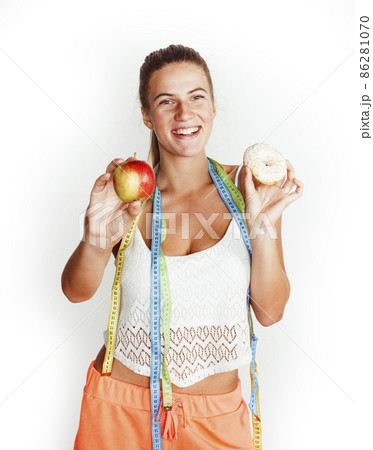 woman measuring waist with tape having choise between apple and donut isolated on white background 86281070