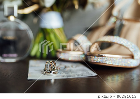 beautiful gold wedding rings on wooden table next to bouquet and shoes 86281615