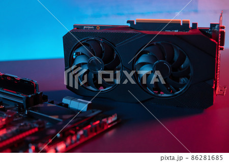 Modern graphic card lies on the desk next to motherboard 86281685