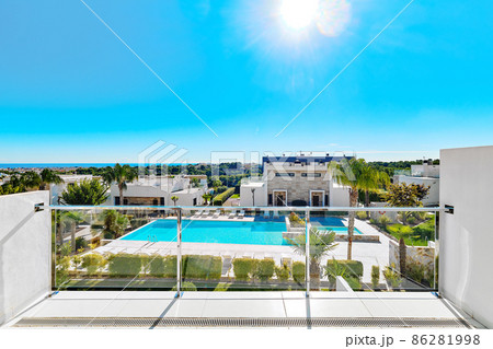 Inner yard with tropical trees, lush plants and swimming pool and summer luxury villas exterior, view form balcony. Spain 86281998