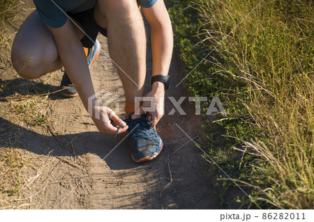 A young man ties the laces on his sneakers. A young man ties the laces on his sneakers. 86282011