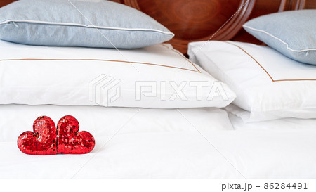 Blurred Romantic interior for Valentine's day with bed. Two red hearts on a white. Blurred Romantic interior for Valentine's day with bed. Two red hearts on a white. 86284491