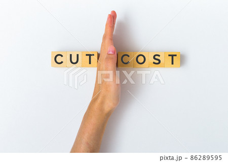 Hand cutting wooden block with text CUT COST, savings, business, recession, wasteful, commission, cash back, taxes, Concept of budget cuts. Hand cutting wooden block with text CUT COST, savings, business, recession, wasteful, commission, cash back, taxes, Concept of budget cuts. 86289595