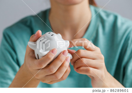 Hand holding piggy bank and trying to get the money out, crisis, financial problems, not enough, financial savings, need for money, business, investment, retirement. Hand holding piggy bank and trying to get the money out, crisis, financial problems, not enough, financial savings, need for money, business, investment, retirement. 86289601