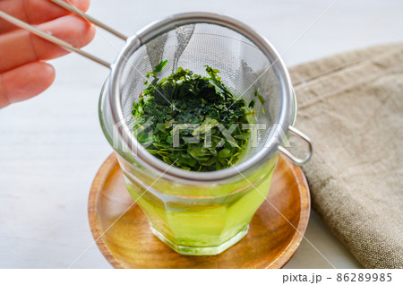 茶こしでグラスに入れる緑茶 86289985