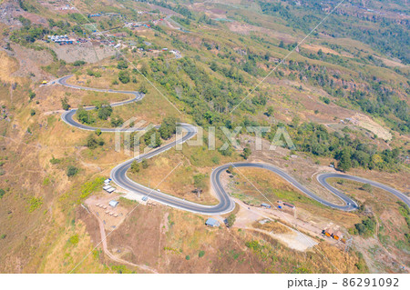 Aerial view of cars driving on curved, zigzag curve road or street on mountain hill with green natural forest trees in rural area of Nan, Thailand. Transportation. Aerial view of cars driving on curved, zigzag curve road or street on mountain hill with green natural forest trees in rural area of Nan, Thailand. Transportation. 86291092