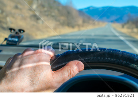driver hand on the steering wheel inside the car 86291921