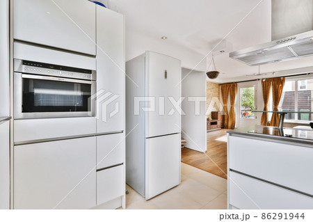 A fascinating kitchen with a mirrored black countertop and beige tiled floor 86291944