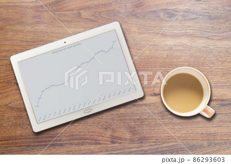 石油価格値上がり推移が写るタブレットとコーヒーカップ（英語） 86293603