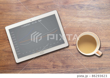 人口動態統計:死亡数推移が映るタブレット端末とコーヒーカップ 86293623