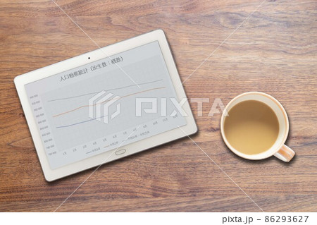 人口動態統計:出生数グラフが映るタブレット端末とコーヒーカップ 86293627