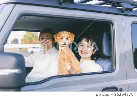車でお出かけする犬と男女（車内） 86294270