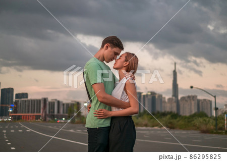 Lovely mix young couple standing on the street in the metropolis on the sunset and cuddling. Love people and happiness. Skyscrapers on the background Lovely mix young couple standing on the street in the metropolis on the sunset and cuddling. Love people and happiness. Skyscrapers on the background 86295825