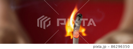 Burning match in hand on red background 86296350