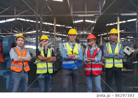 A group of industry workers and engineers of various races enjoy working in a heavy plant and stand together with a pleasant smile. portrait A group of industry workers and engineers of various races enjoy working in a heavy plant and stand together with a pleasant smile. portrait 86297383