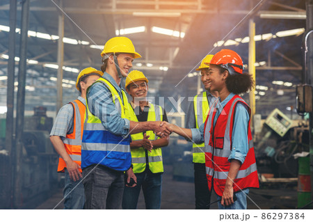A group of industry workers and engineers of various races enjoy working in a heavy plant and stand together with a pleasant smile. portrait A group of industry workers and engineers of various races enjoy working in a heavy plant and stand together with a pleasant smile. portrait 86297384