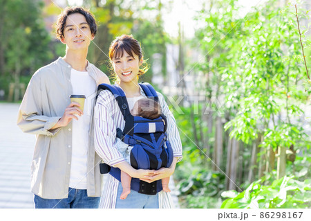 赤ちゃんを抱っこしながら外を歩く夫婦 86298167