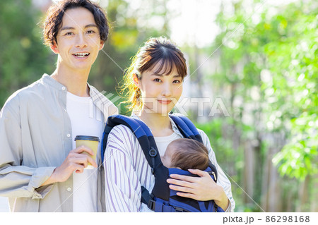 赤ちゃんを抱っこしながら外を歩く夫婦 86298168