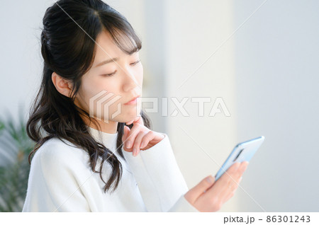 スマホで悩む日本人女性 右にコピースペースあり スマホで悩む日本人女性 右にコピースペースあり 86301243