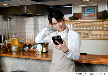 飲食店(レストラン)で悩むエプロン姿のアジア人の男性 飲食店(レストラン)で悩むエプロン姿のアジア人の男性 86303431