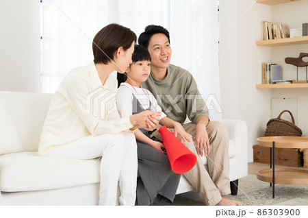 テレビでスポーツ観戦する親子3人のファミリー 86303900