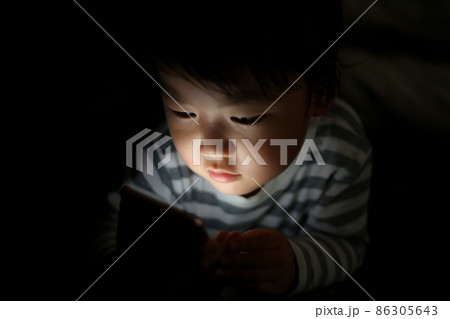 暗い中でスマートフォンを使う男の子 86305643