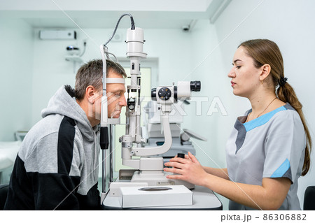 Ophthalmologist and patient testing eyesight. Man doing eye test with optometrist. Ophthalmologist using apparatus for eye examination in clinic. Doctor examining patient doing eyesight measurement Ophthalmologist and patient testing eyesight. Man doing eye test with optometrist. Ophthalmologist using apparatus for eye examination in clinic. Doctor examining patient doing eyesight measurement 86306882