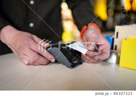 Salesman holds payment terminal while holding receipt for completing purchase. Hands close up. Concept of NFC, business and banking transactions. Payment terminal with paper tape. Bank terminal 86307325