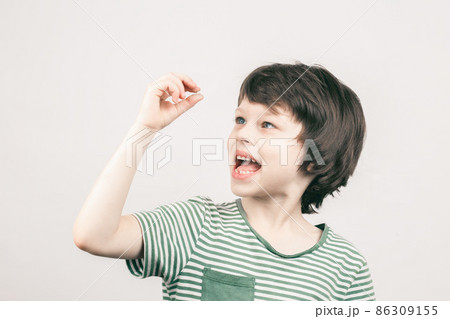 Young boy looking at his first lost milk tooth Young boy looking at his first lost milk tooth 86309155
