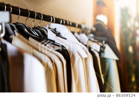 Clothes hang on a shelf in clothes store. Clothes for women hanging on hangers in home closet or shopping mall for store sale concept. Clothes hang on a shelf in clothes store. Clothes for women hanging on hangers in home closet or shopping mall for store sale concept. 86309524