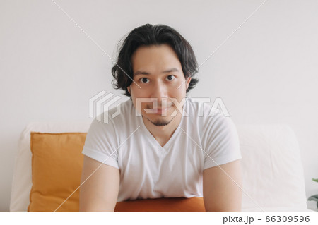 Happy smile face long hair man sit and relax on the sofa in living room. 86309596