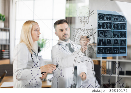 Two doctors examining x ray scan at office Two doctors examining x ray scan at office 86310172