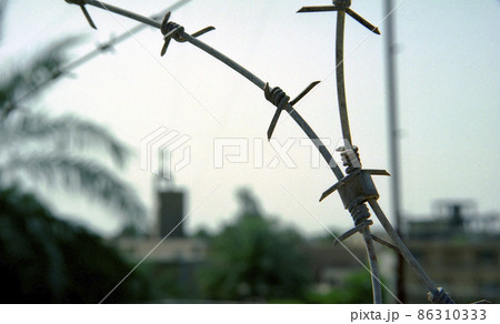 Old rusty security barbed wire fence on blue sky Old rusty security barbed wire fence on blue sky 86310333
