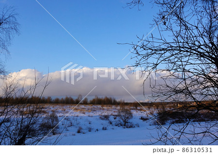 Winter background. The river is covered with ice. Blue sky with big cloud. Russia. 86310531