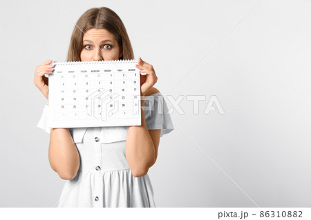 Excited young woman holding calendar with marked menstrual cycle days on beige background Excited young woman holding calendar with marked menstrual cycle days on beige background 86310882