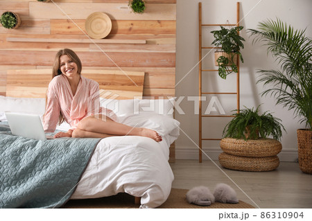 Woman using laptop in bedroom with green plants. Home design ideas 86310904