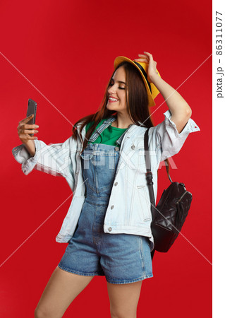 Young woman taking selfie on red background Young woman taking selfie on red background 86311077