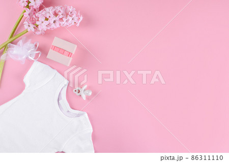 baby girl bodysuit, nipple or baby's dummy, gift box and confetti and hyacinth flowers on pink background, flat lay baby girl bodysuit, nipple or baby's dummy, gift box and confetti and hyacinth flowers on pink background, flat lay 86311110