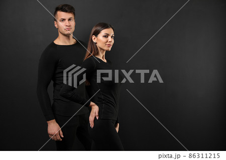 Couple wearing thermal underwear on black background. Space for text 86311215