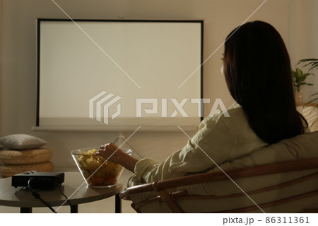 Young woman watching movie using video projector at home 86311361