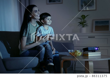 Young mother and her son watching movie using video projector at home 86311375