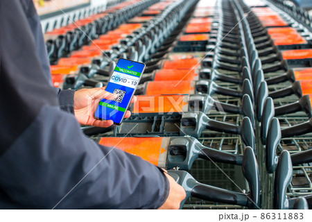 Man with covid certificate on smartphone  which allows him to buy goods 86311883