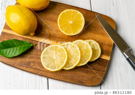 Whole lemon and juicy slices on a brown wooden chopping board. Whole lemon and juicy slices on a brown wooden chopping board. 86312180