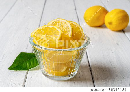 Juicy lemon slices in a glass bowl on an old white wooden table. Juicy lemon slices in a glass bowl on an old white wooden table. 86312181