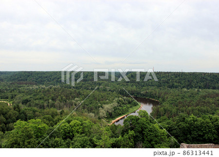 River Gauja and National park Gauja with pine forest in a cloudy day. Aerial view from tower of Turaida Castle in Sigulda, Latvia. River Gauja and National park Gauja with pine forest in a cloudy day. Aerial view from tower of Turaida Castle in Sigulda, Latvia. 86313441