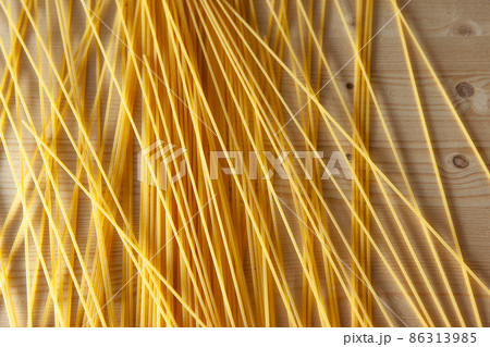 Food theme: raw pasta as whole background. Yellow Spaghetti scattered on the table with black pepper peas. Italian food concept. High-quality photo 86313985