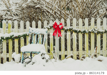 雪に埋もれた赤いリボンとイス 86314179